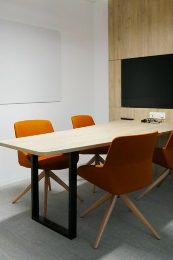 espace de travail fermé avec un écran tv au mur et une table et sièges de bureau