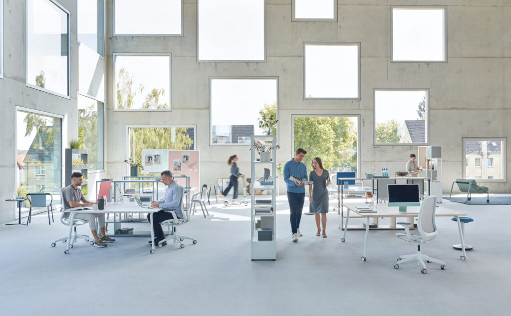 un grand espace de travail avec des personnes assises a une table et d'autres debout qui échangent