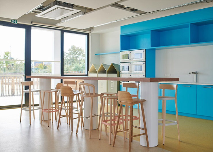 Un espace cuisine avec des éléments de cuisine bleus, une table haute avec des tabourets hauts en chêne couleur naturelle