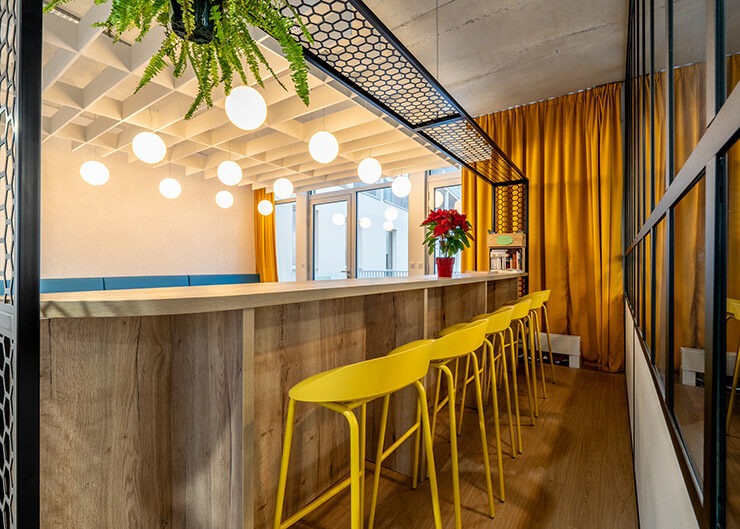 Un espace lounge avec un bar agencé et des tabourets hauts jaunes