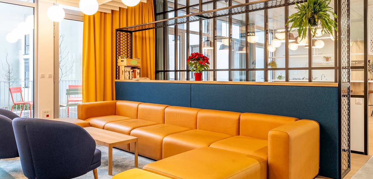 un espace caféteria avec un grand canapé jaune et une petite table basse