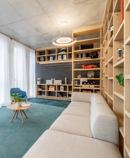 Un espace accueil avec un grand canapé beige et des étagères en bois le long du mur