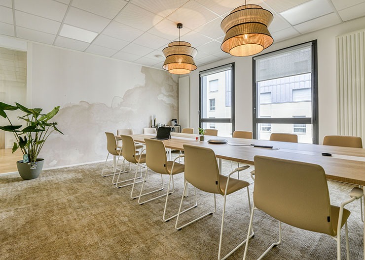 un espace réunion avec une grande table des sièges de travail une moquette au sol