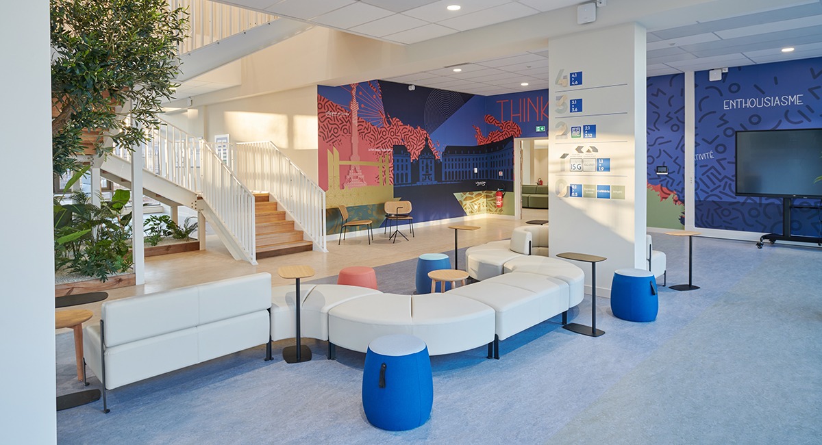 Un espace accueil avec une longue banquette blanche, un pouf bleu