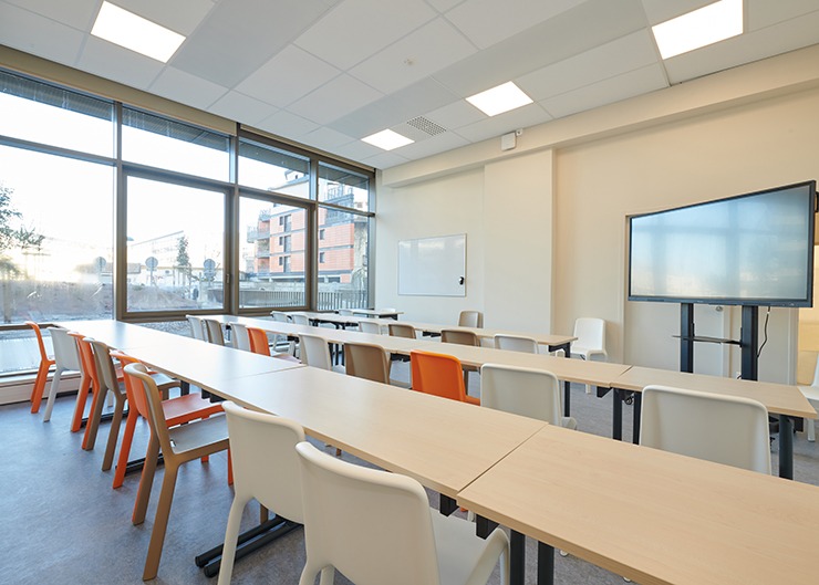 une salle de classe étudiante avec des chaises et de longues tablees blanches