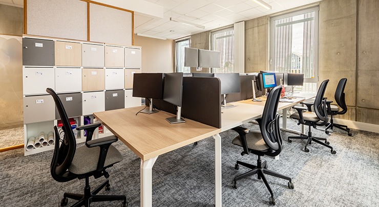 un vaste espace de bureau avec des espaces de travail, des fauteuils et des pc