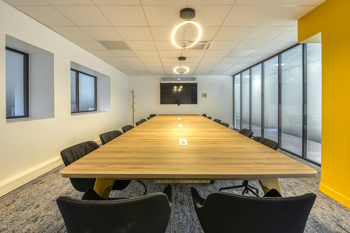 un vaste espace de réunion avec une grande table de reunion et des sièges de travail