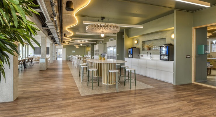 Vaste espace caféteria workcafé avec une cuisine aménagée une grande table et des tabourets hauts