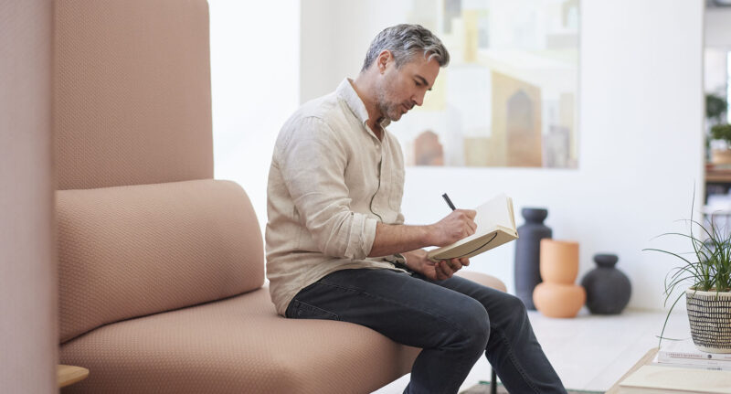 un homme seul assis ecrivant sur un cahier