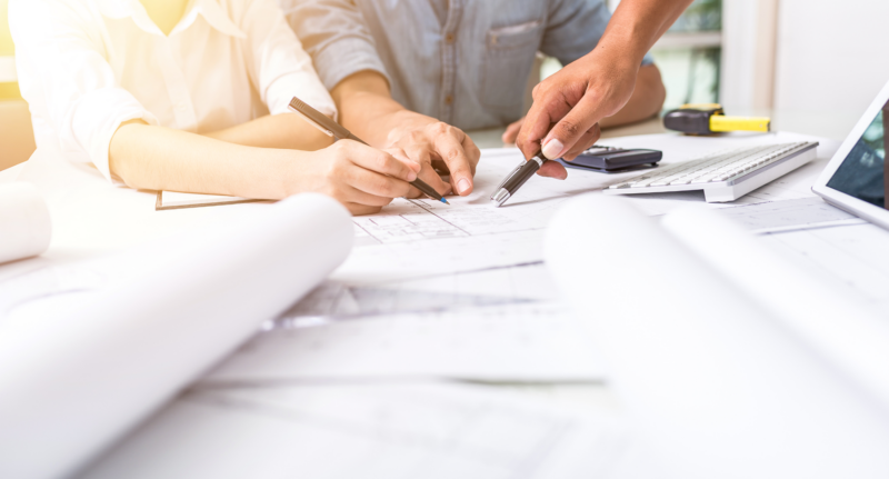 un plan de conception, des mains qui pointent sur ce plan