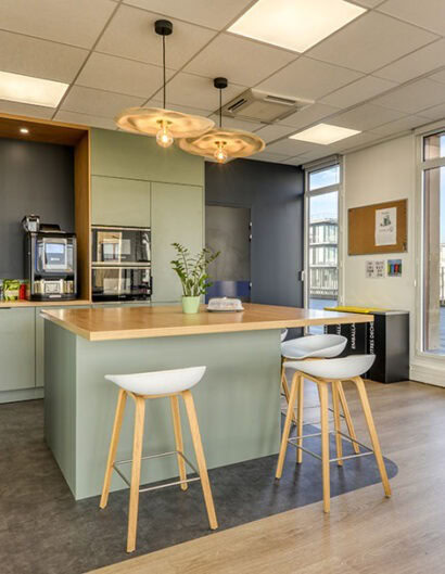 un espace cuisine avec un ilot central des tabourets hauts